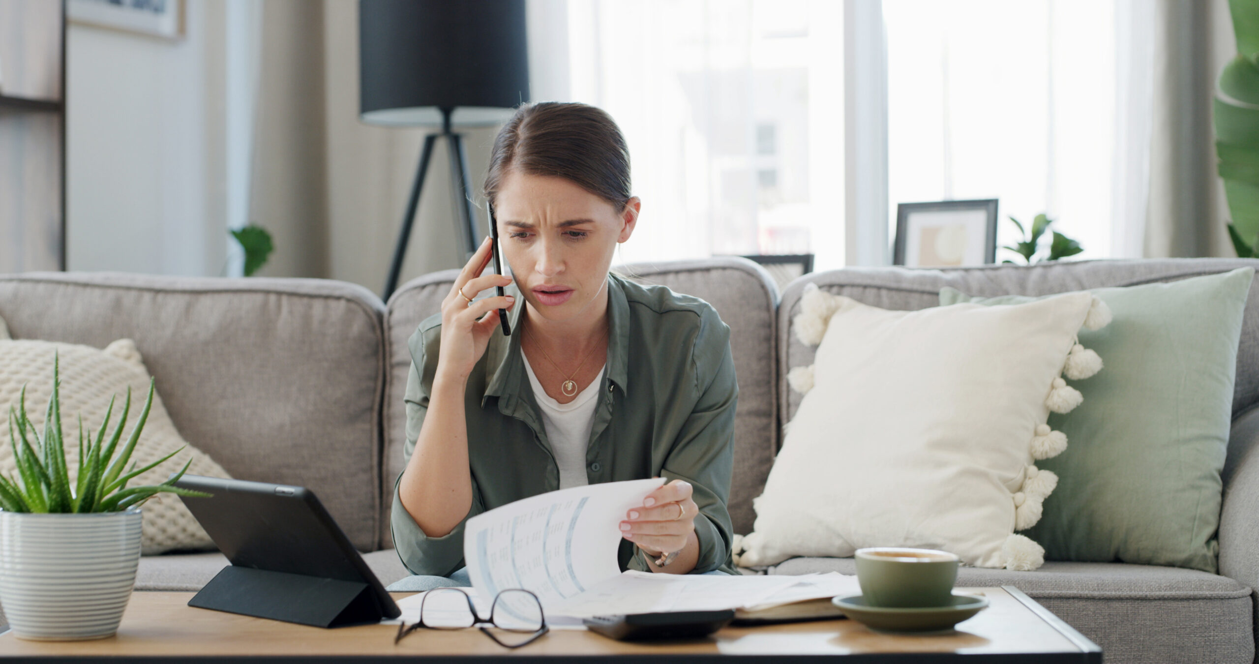 Concerned woman on phone reviewing documents at home