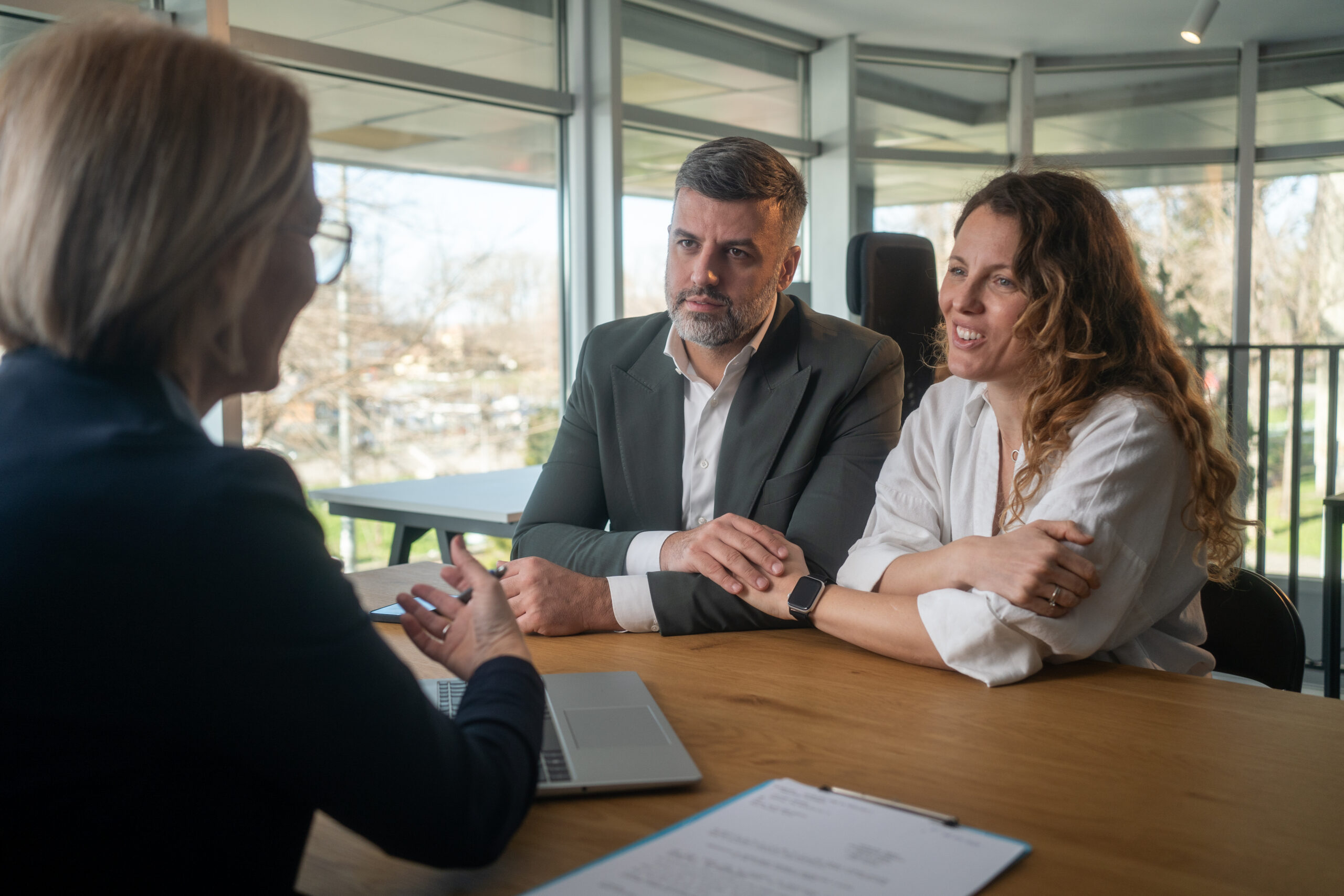 Couple consulting with a professional across a desk in a sunlit office