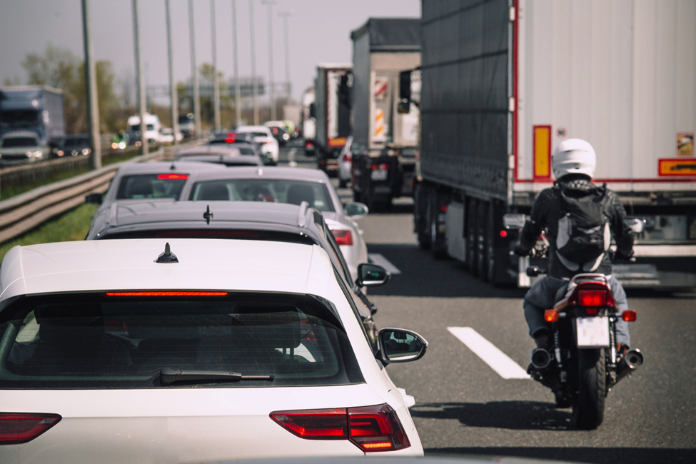 a busy highway with cars, trucks, and a motorcycle