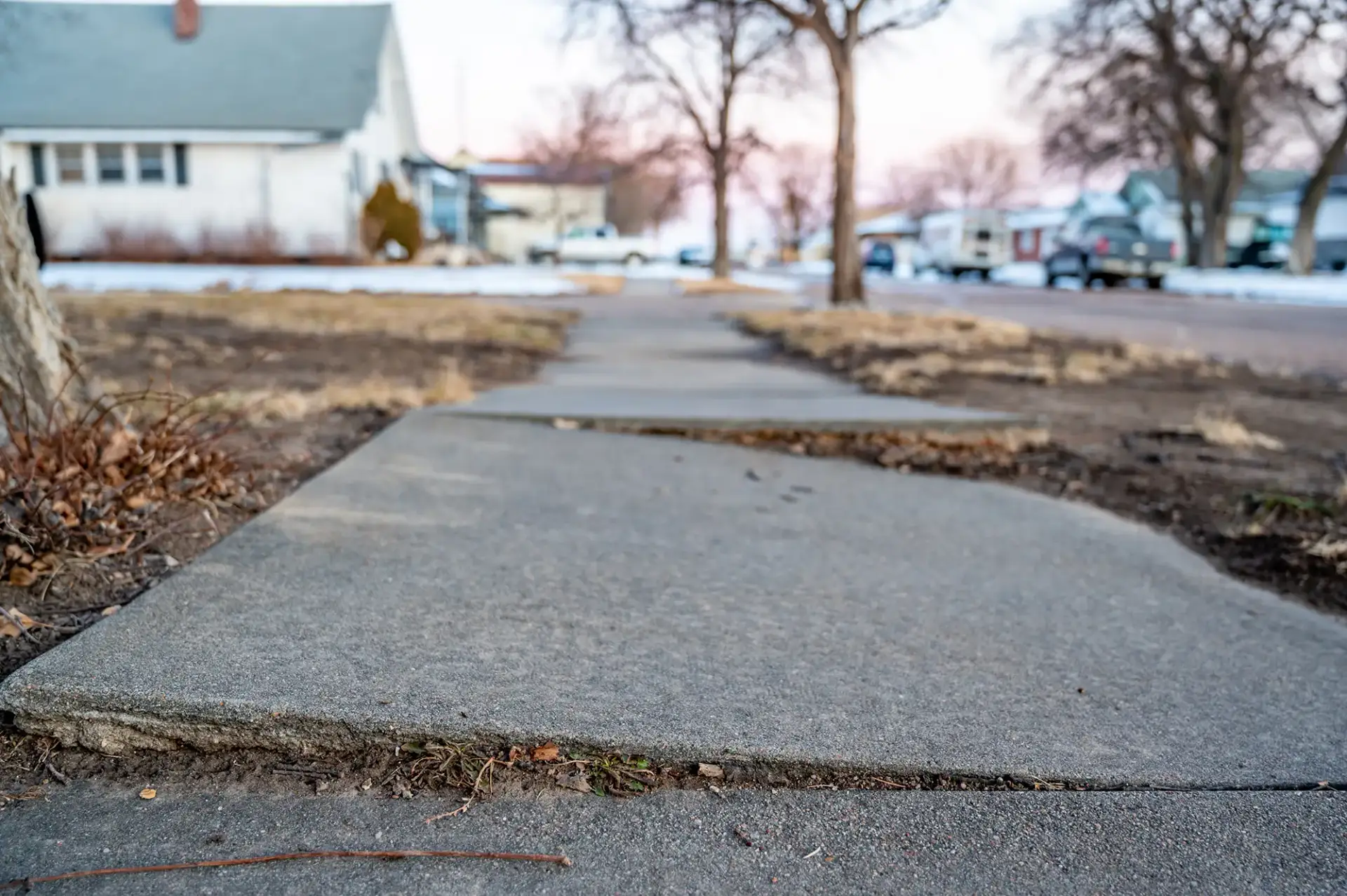 Uneven and raised concrete sidewalk creating a tripping hazard in a residential neighborhood