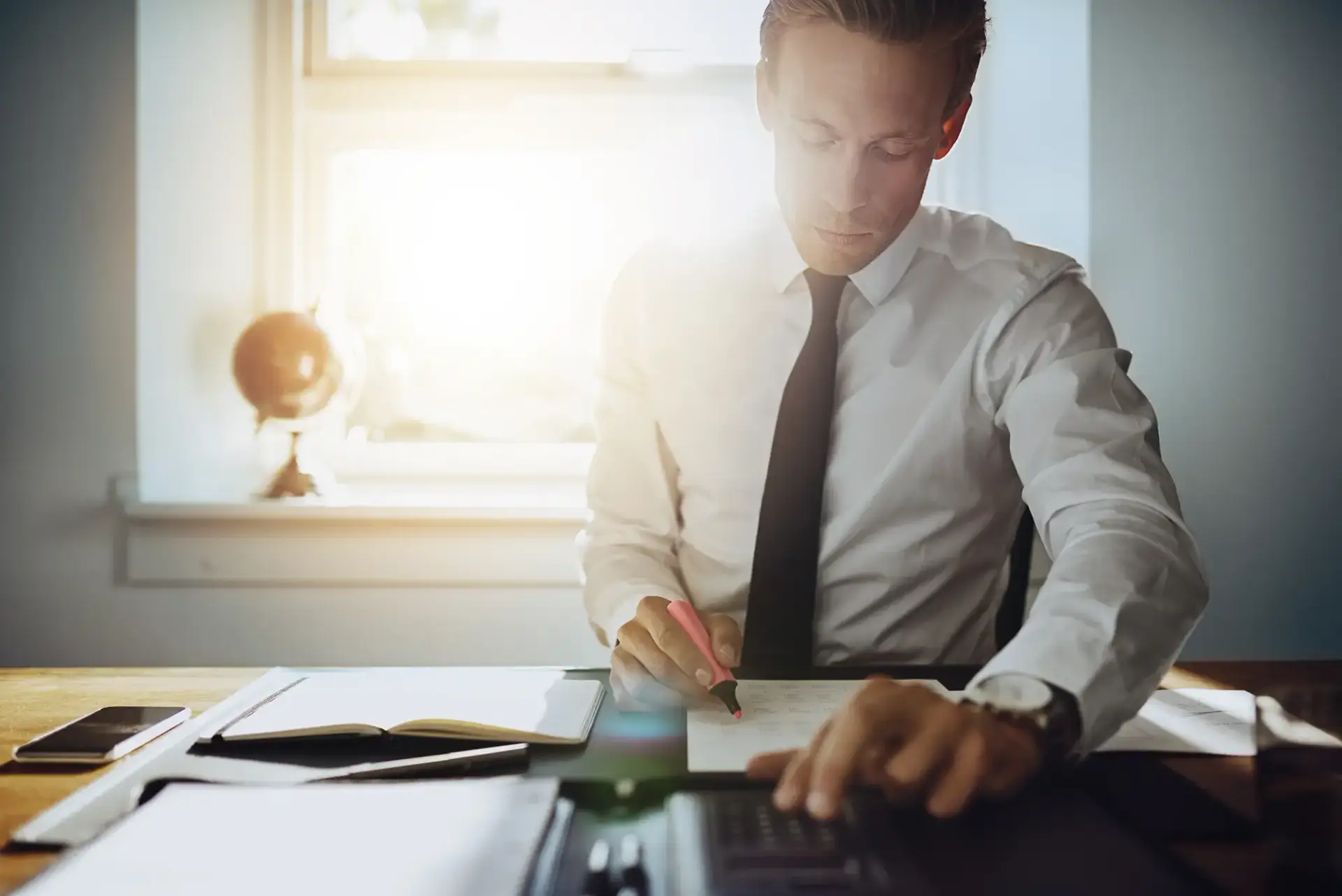 Attorney reviewing case documents and calculating damages at a sunlit desk